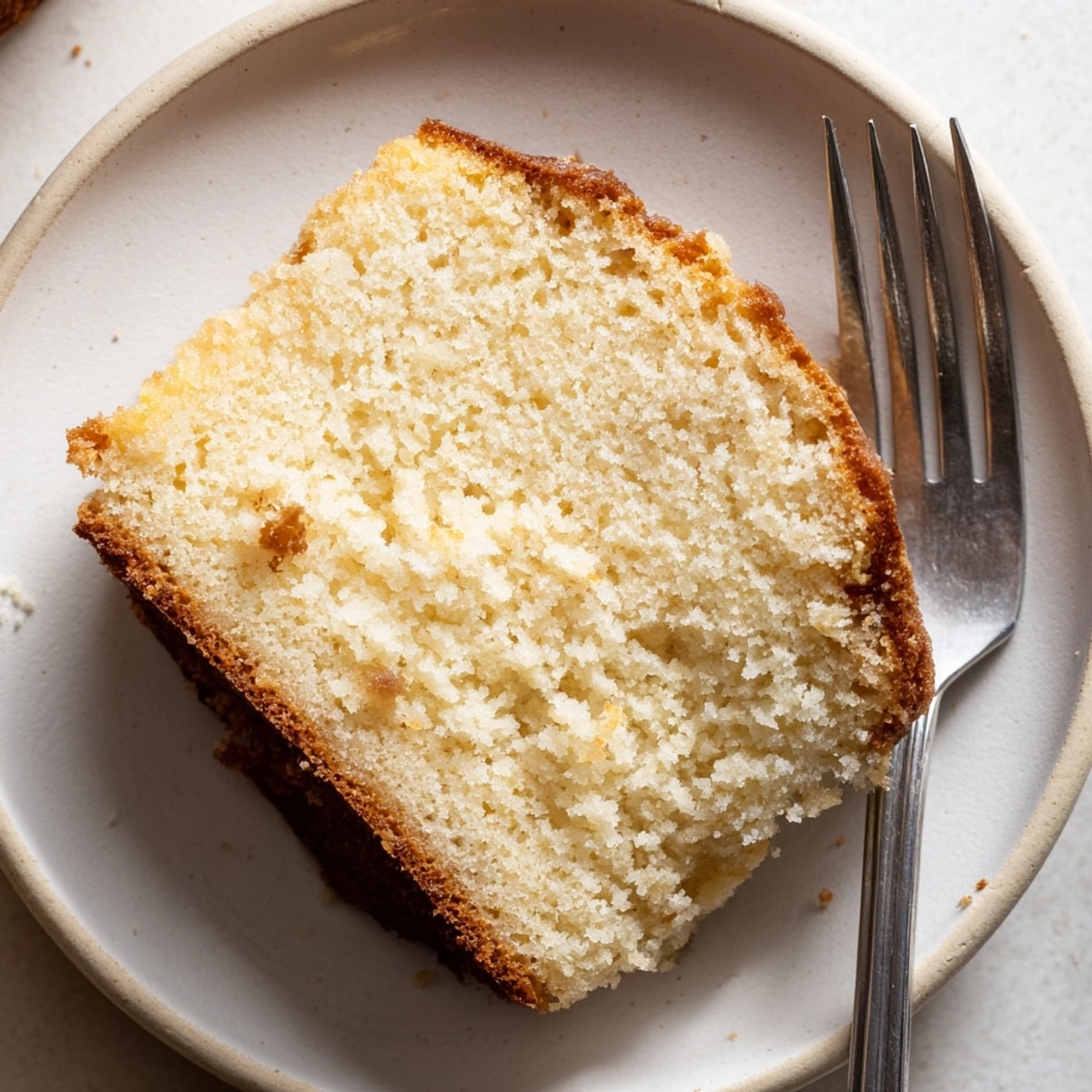 Freshly baked French Vanilla Pound Cake: moist, golden brown, perfect slice with powdered sugar.