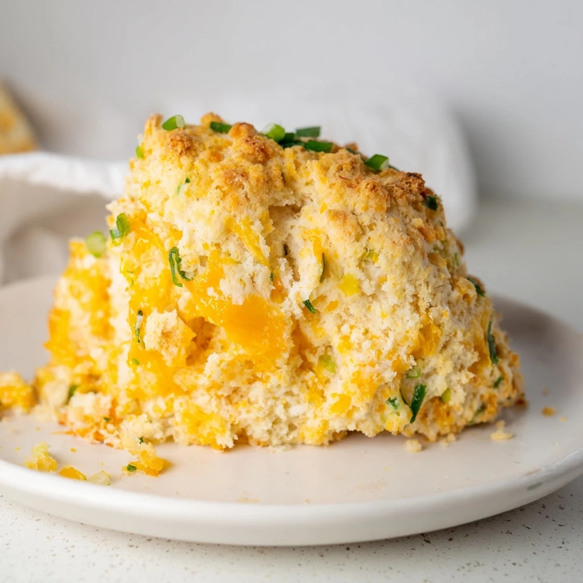 A close-up of buttery savory cheese scones, showcasing the melted cheddar cheese and fresh herbs.