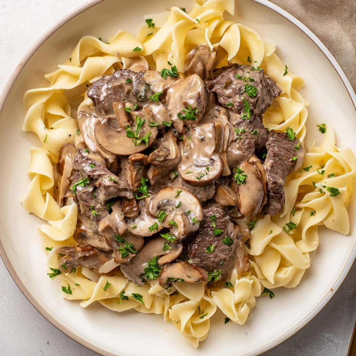 A close-up of hearty Rich Beef Stroganoff with warm, inviting gravy and fresh parsley garnish.