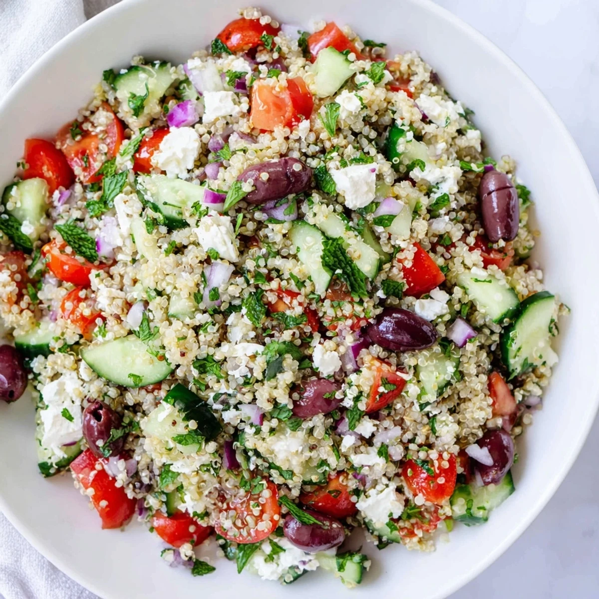 Freshly assembled Mediterranean quinoa salad with feta, drizzled with zesty lemon-oregano dressing.