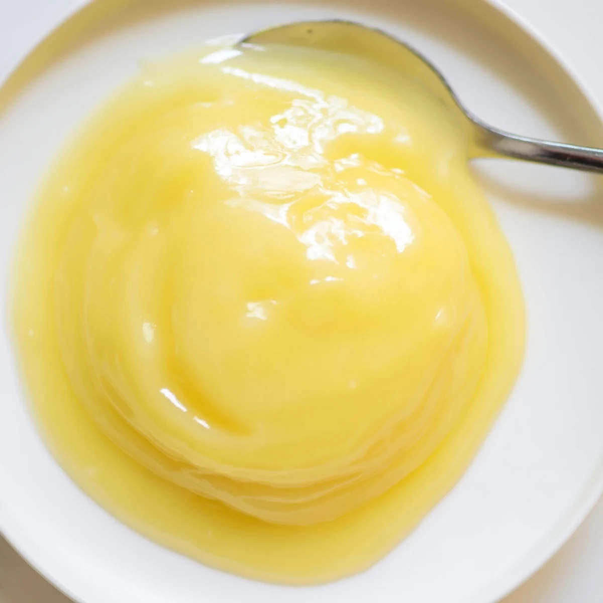 Vibrant yellow swirls of creamy lemon curd, ideal to be a tart filling or a dessert spread.