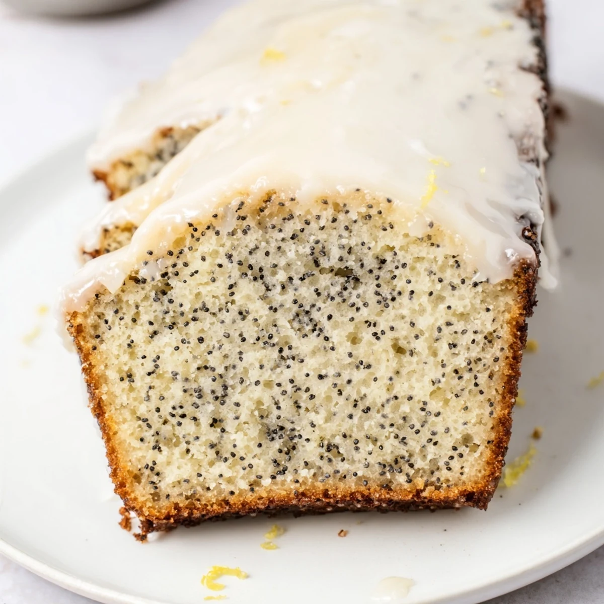 A close-up of a freshly baked Lemon Poppy Seed Loaf with visible poppy seeds and a golden crust.