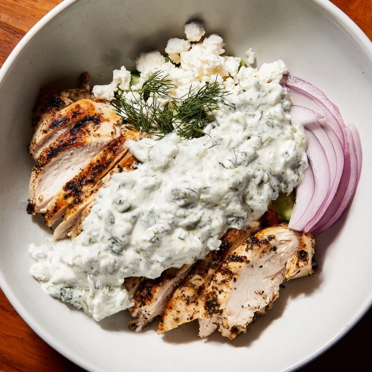Sliced marinated chicken and vibrant vegetables over rice in Greek Chicken Gyro Bowls with Tzatziki Sauce.