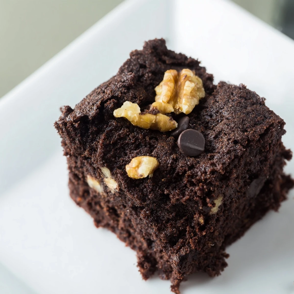 Golden-edged Gluten Free Almond Flour Brownies piled on a white plate with a glass of milk nearby.