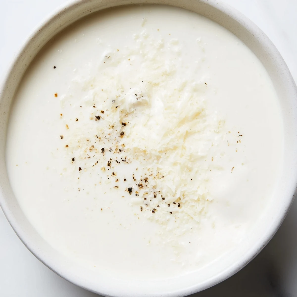 A bowl of silky Creamy Milk Sauce garnished with fresh parsley, ideal for drizzling over baked potatoes or gratins.