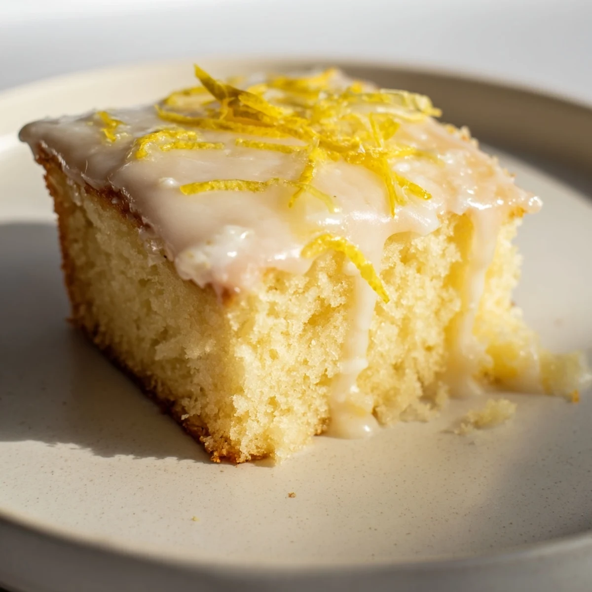Lemon Cake Slice served on a saucer with tea, powdered sugar lightly dusted on top.