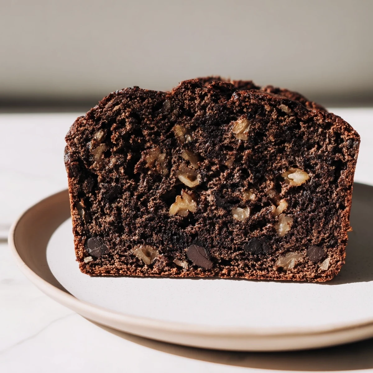 Freshly baked Chocolate Banana Bread with gooey chocolate chips on a cooling rack, slice removed.