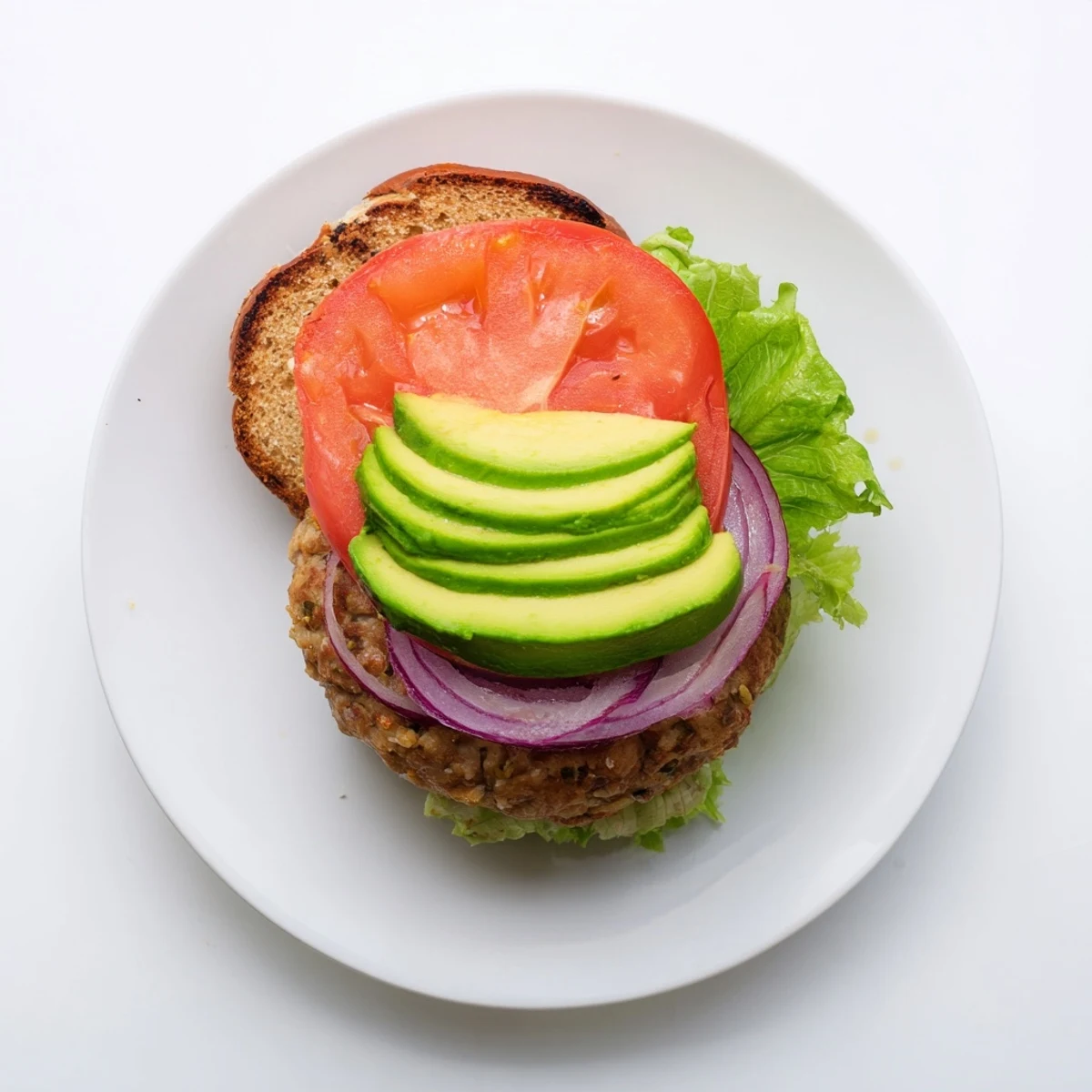 Close-up of a juicy turkey burger with creamy avocado slices, crisp lettuce, and a toasted bun.