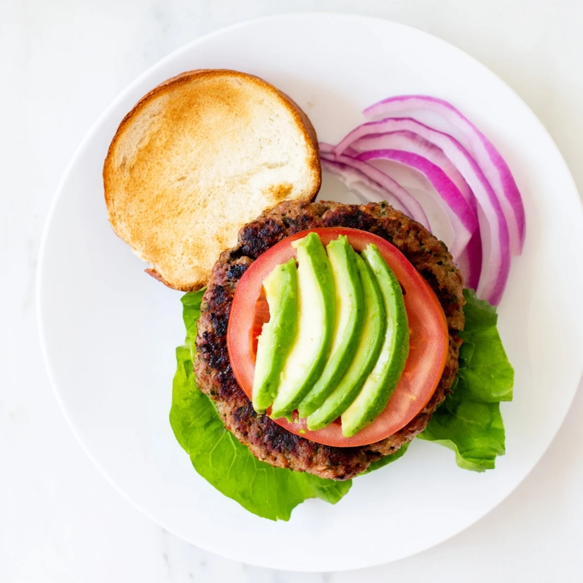 Golden-brown turkey burger patties sizzling on a skillet, ready for assembly with fresh toppings.