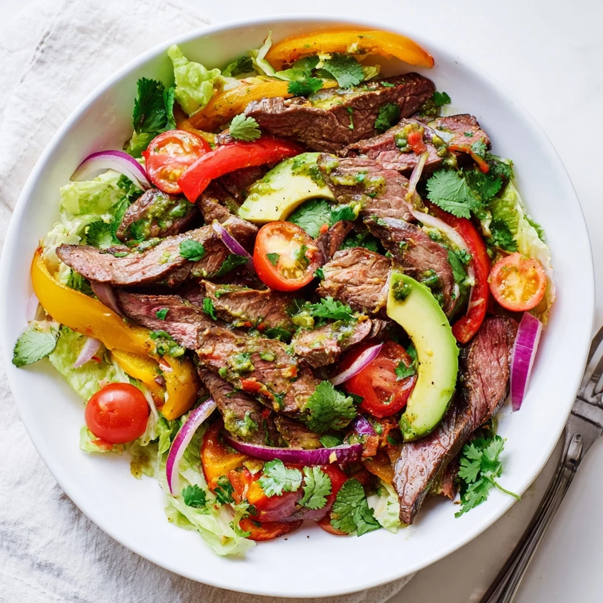 This Tex-Mex inspired main dish salad features warm beef strips, juicy halved cherry tomatoes, and fresh cilantro, all ready to be tossed with a zesty, homemade lime dressing.  