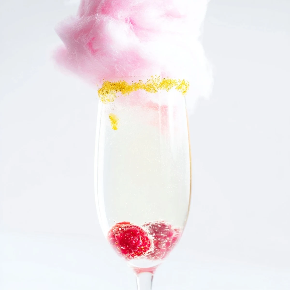 Refreshing pink champagne mocktail with cotton candy garnish and fresh berries, ready to serve in elegant flutes for a whimsical, non-alcoholic celebration toast.
