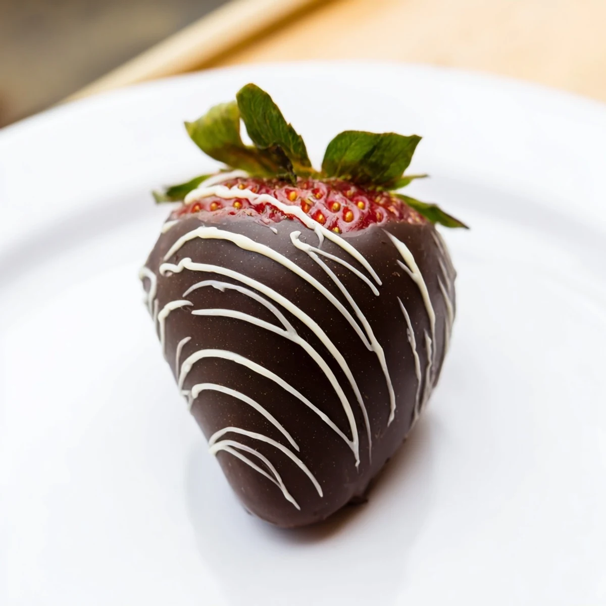 Juicy whole strawberries dipped in dark chocolate, drizzled with white chocolate, presented on a white ceramic plate for a party.  