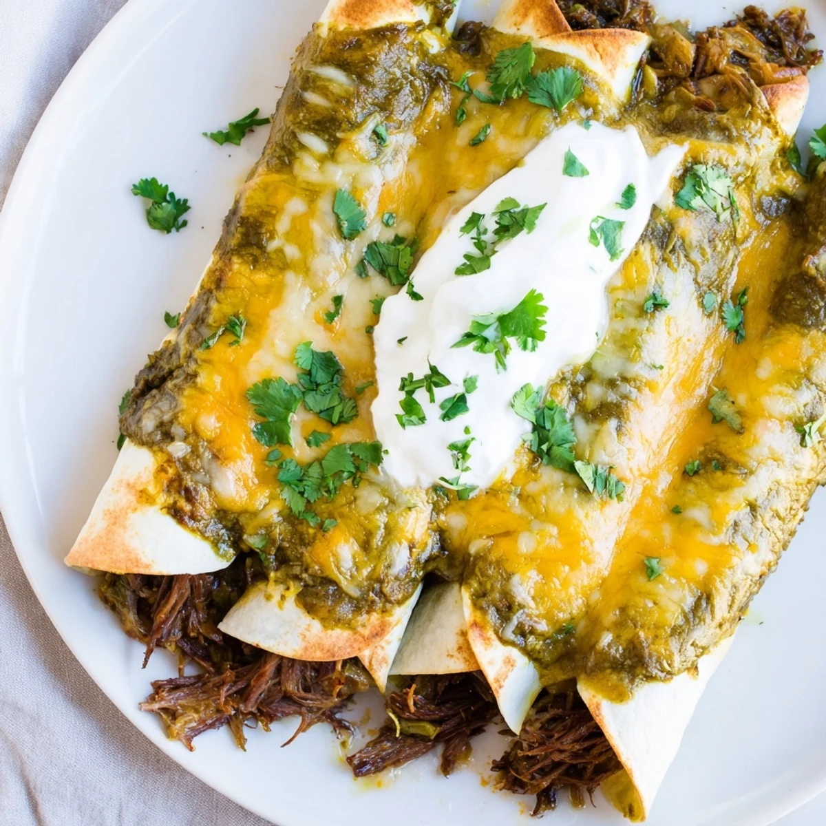 Steam rises from the baked Beef Enchiladas with Green Sauce, with melted cheese bubbling over the tangy green sauce and garnished with fresh cilantro.