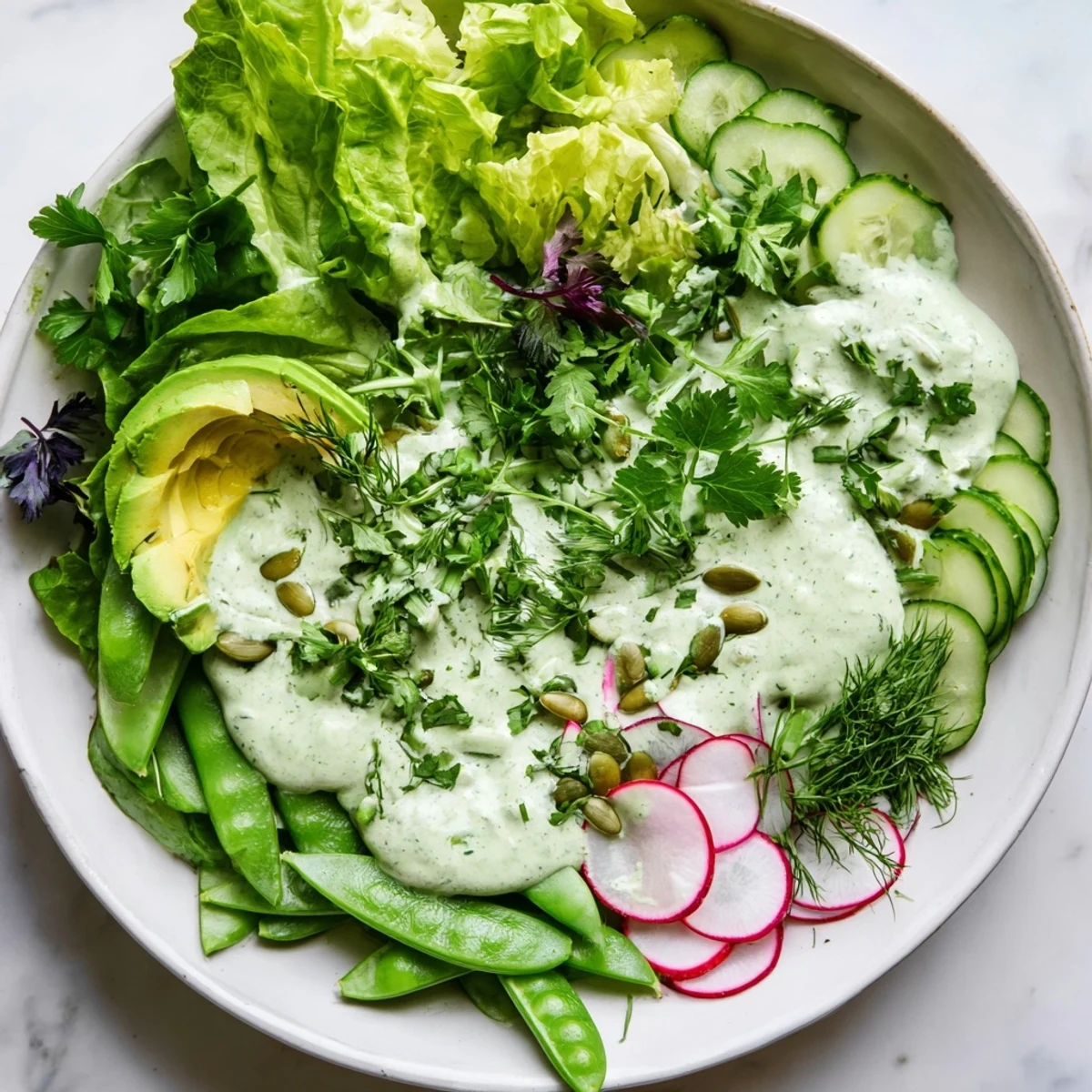 In a white bowl, the Green Salad with Green Goddess Dressing offers a refreshing lunch topped with toasted pumpkin seeds.