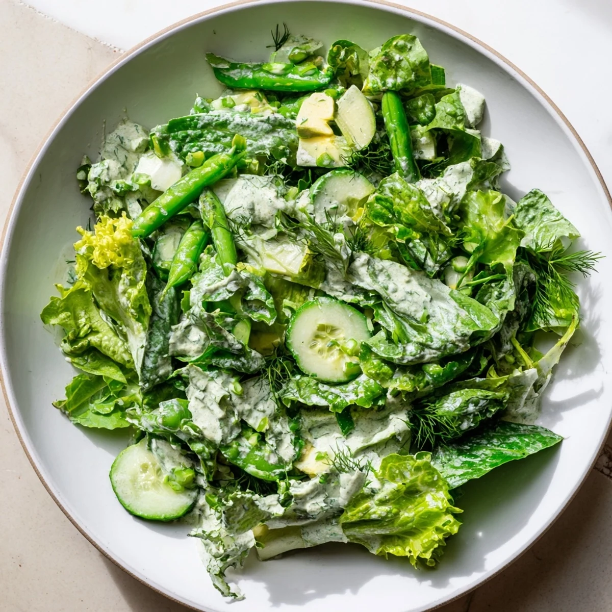 Vibrant Green Salad with Green Goddess Dressing served in a bowl with herbs and onions for extra flavor.