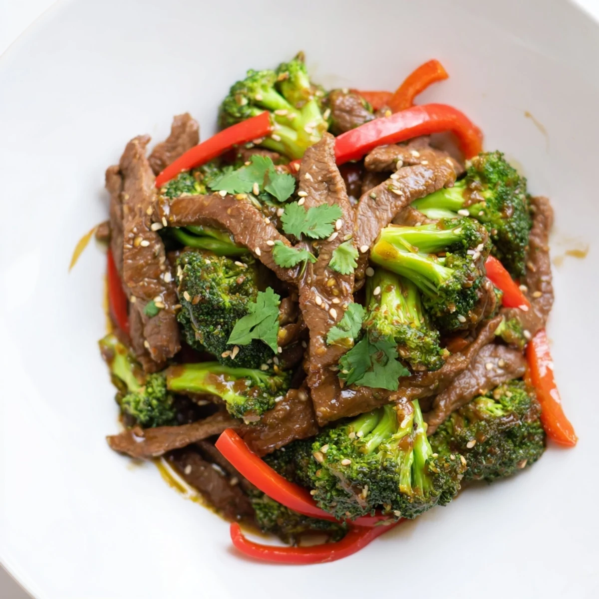 A quick, dairy-free Spicy Beef and Broccoli Stir Fry in a wok, garnished with sesame seeds and scallions.