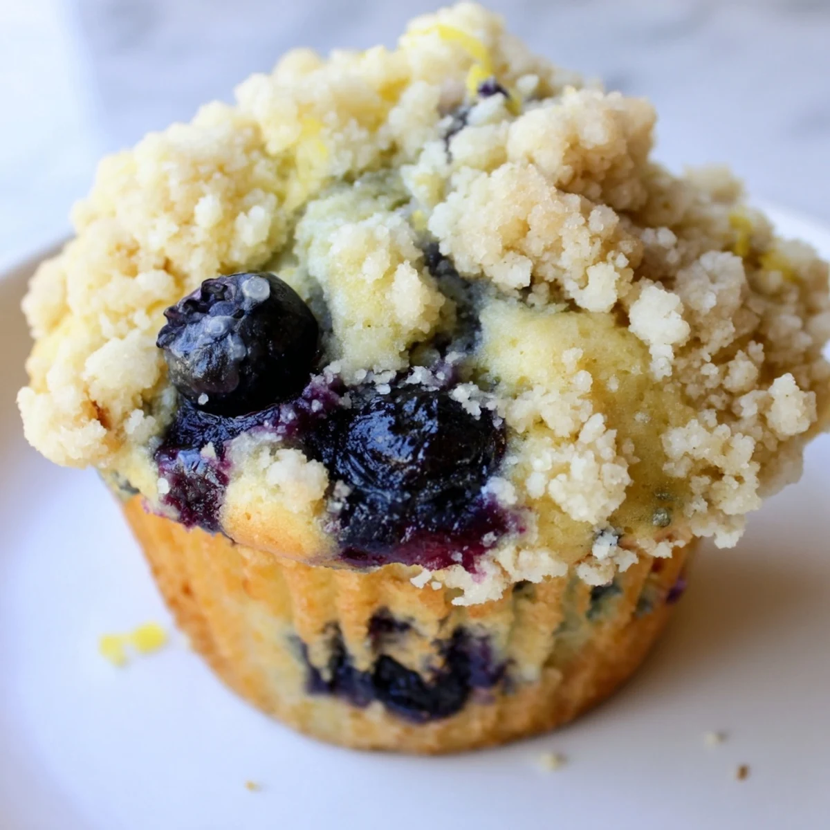 Twelve golden Lemon Blueberry Muffins with Streusel Topping rest on a wire rack, their sugary crust glistening.