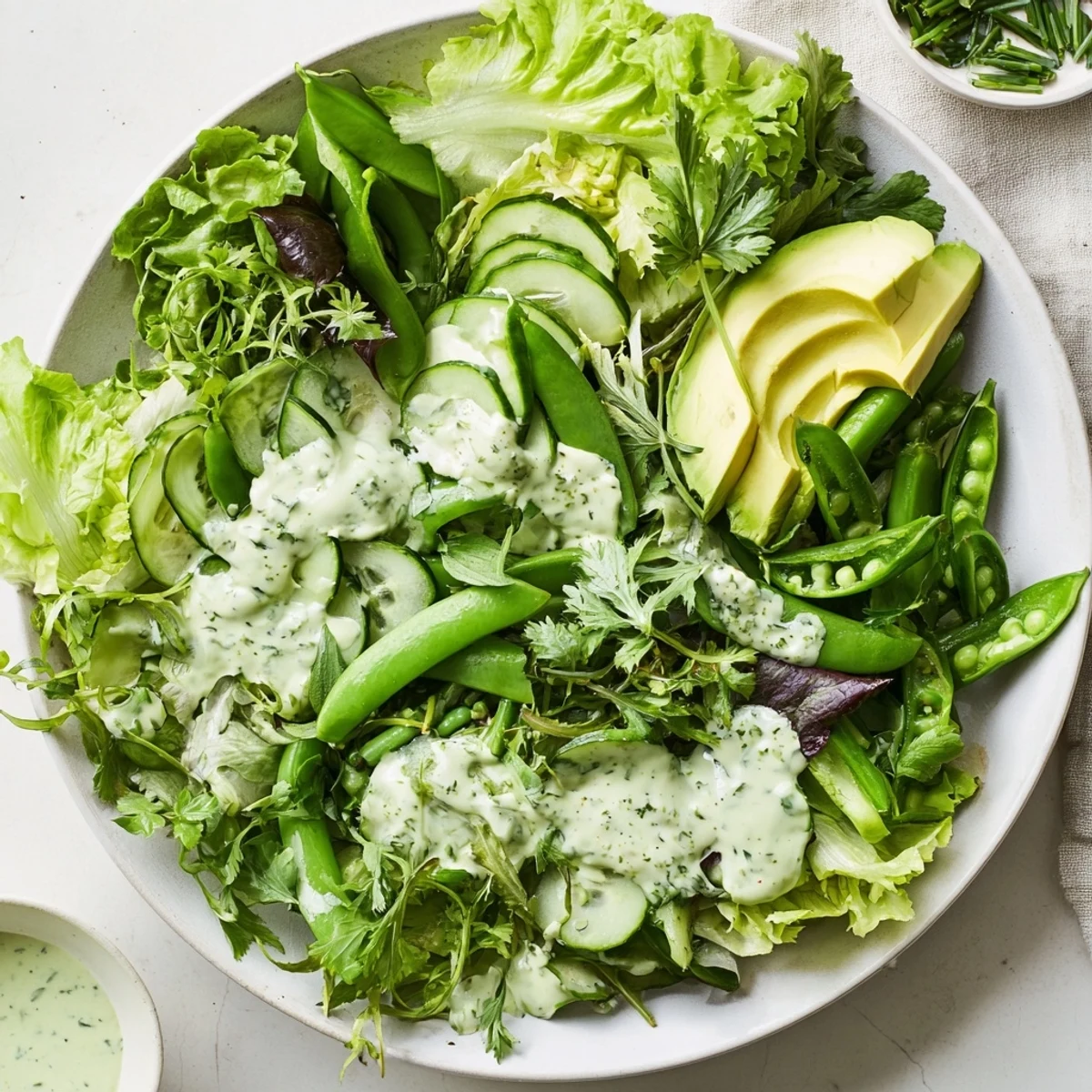 Vibrant Green Salad with Green Goddess Dressing tossed with snap peas, bell pepper, and fresh herbs.