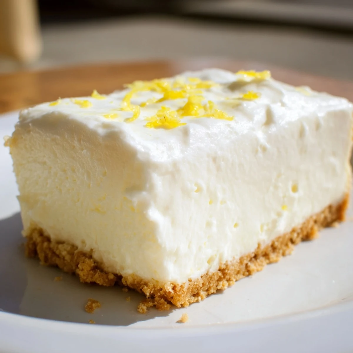 Golden-brown graham cracker crust cradling creamy Rich Greek Yogurt Cheesecake, dusted with powdered sugar and sliced for serving.