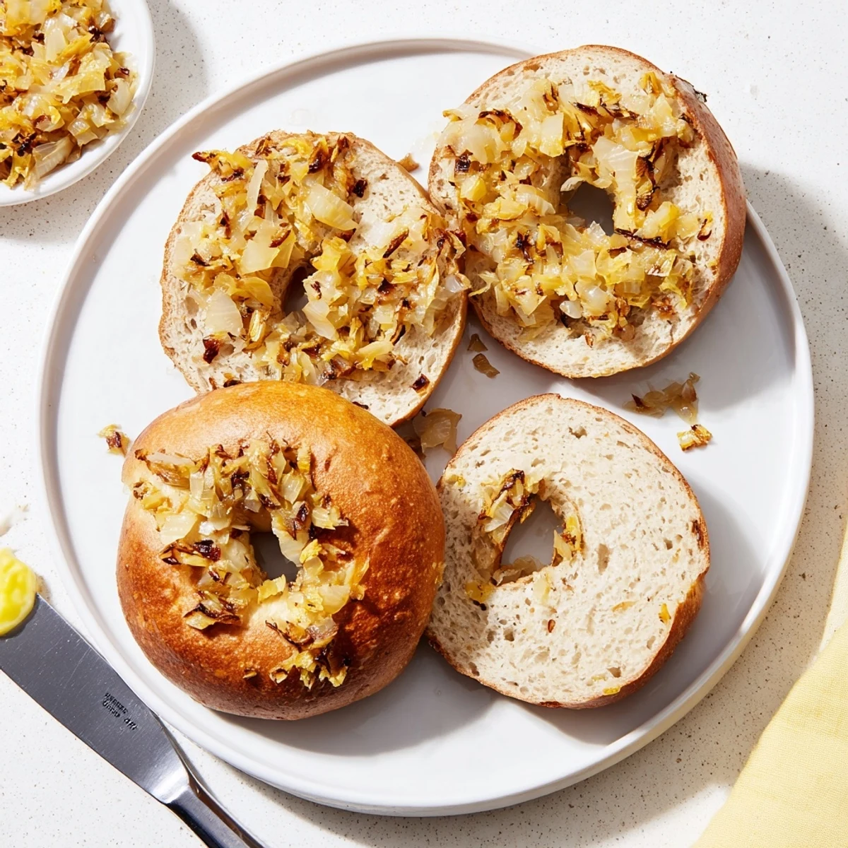 A rustic plate of Sourdough Onion Bagels served with cream cheese spread and fresh herbs for a savory breakfast.