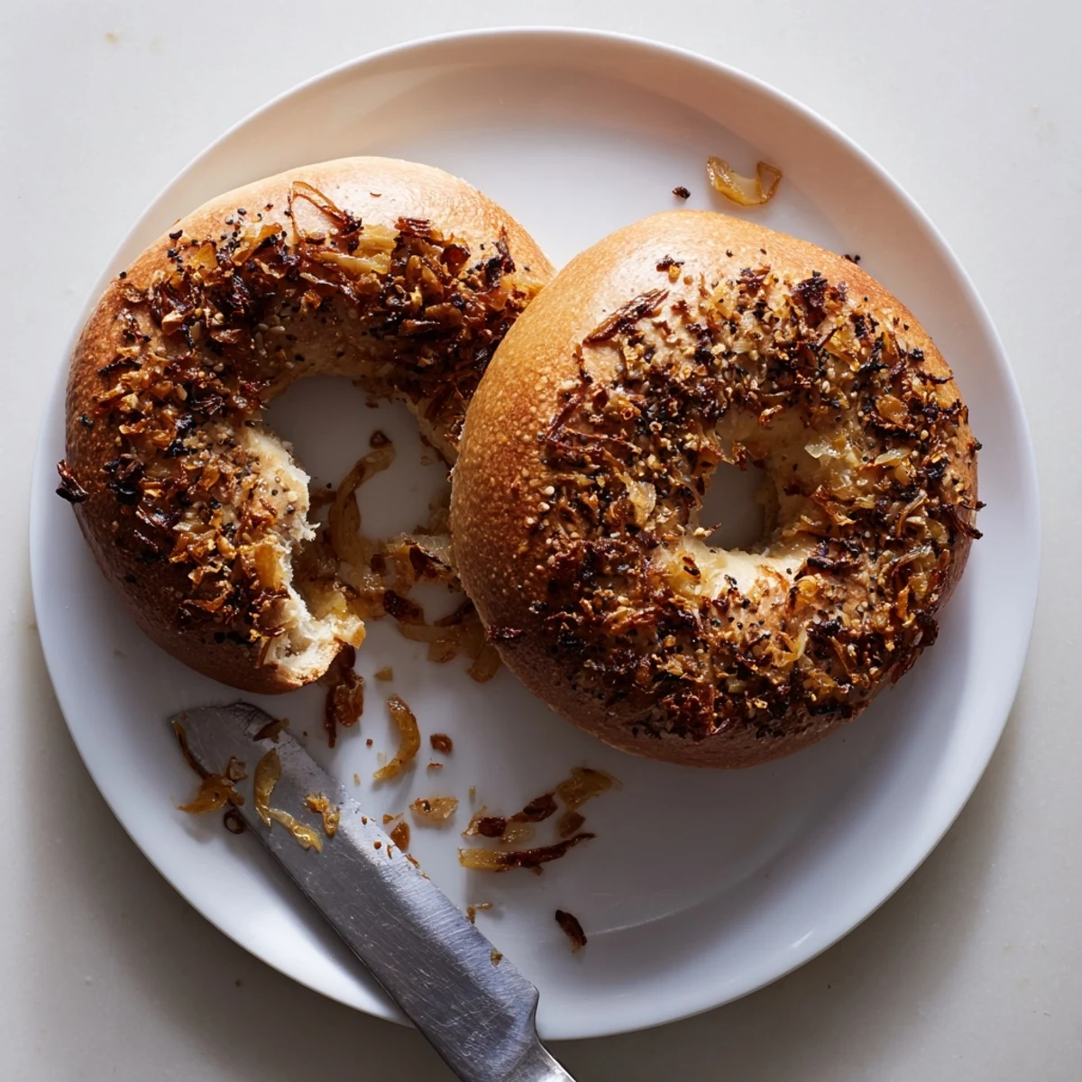 Crackly Sourdough Onion Bagels with chewy interiors and sweet onion topping, sliced open to reveal airy sourdough crumb texture.
