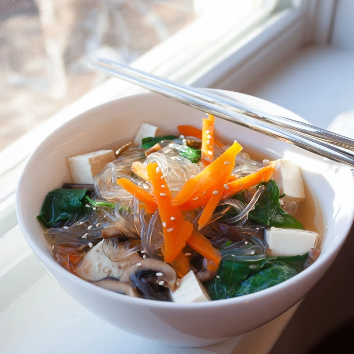 A close-up of Japanese Harusame Noodle Soup with vibrant baby spinach and tofu cubes swimming in a savory dashi broth.
