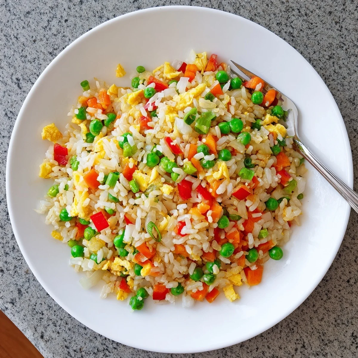 A serving of golden Fried Rice on a plate, garnished with extra green onions and ready to enjoy as a main course.