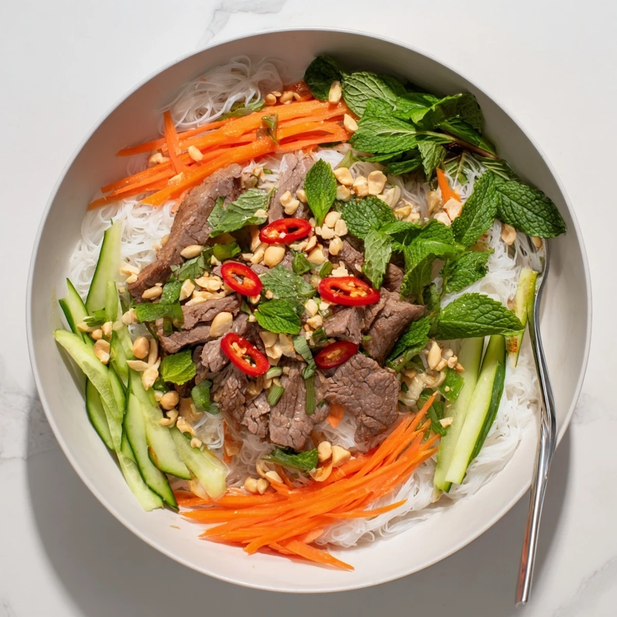 Vibrant Bun Bo Xao platter garnished with roasted peanuts, cilantro, and a slice of lime.