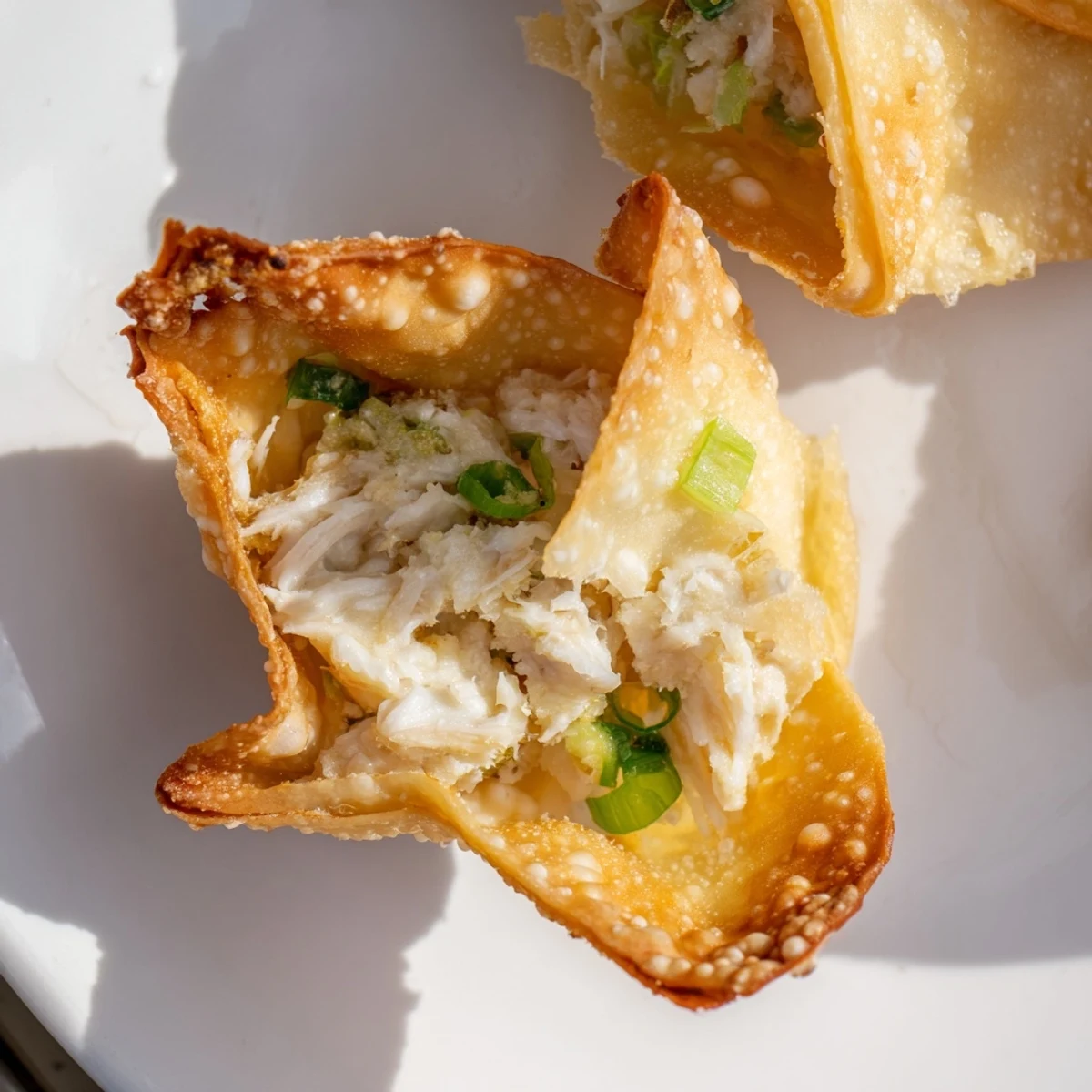 Close-up of Crispy Crab Rangoon Bombs on a platter, garnished with chives and ready to serve.