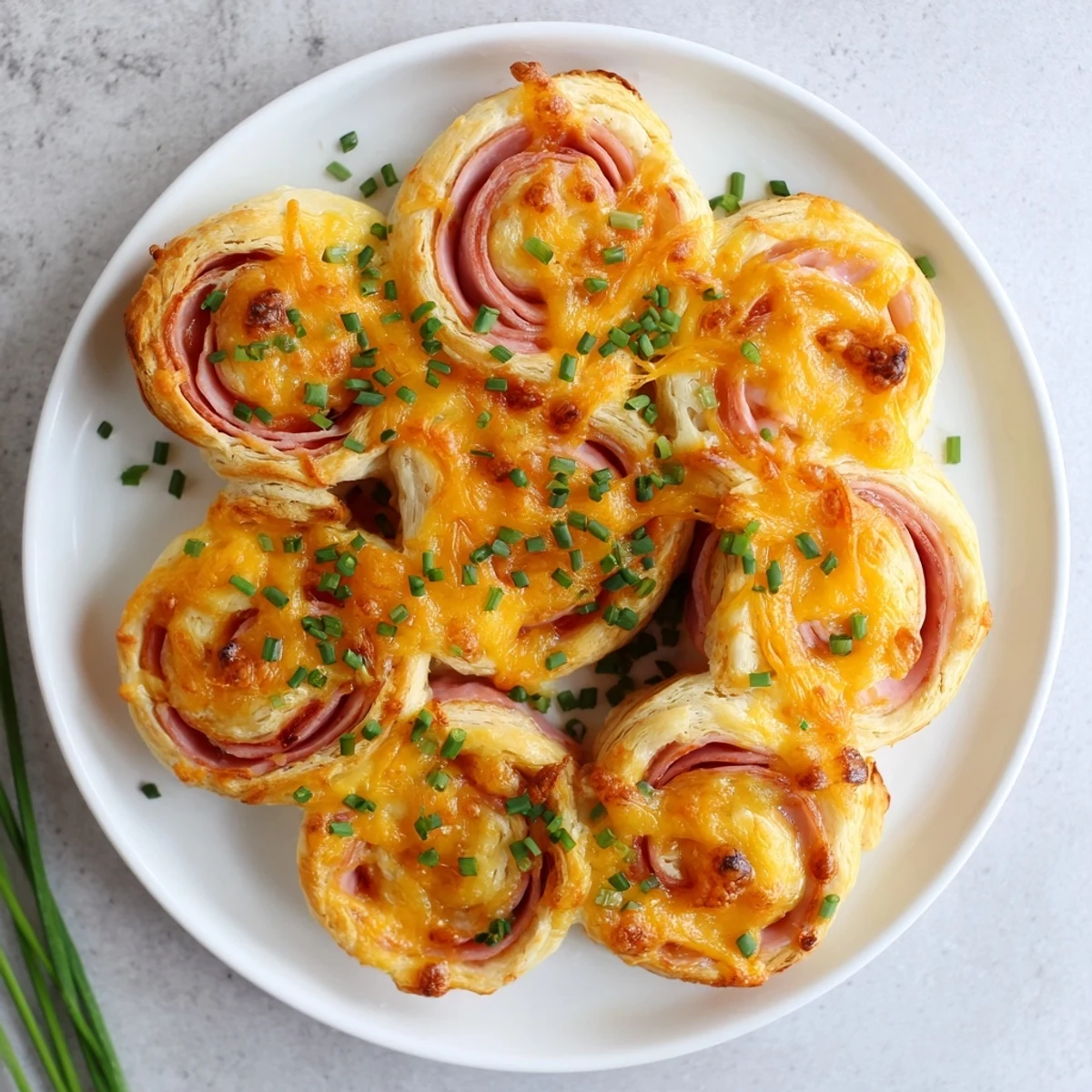 Golden, flaky Easter Ham Cheddar Pinwheels fresh from the oven on a rustic wooden board.