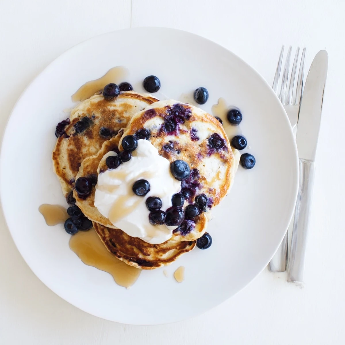 Indulgent Greek Yogurt Blueberry Pancakes served warm with a dollop of yogurt and a drizzle of honey beside coffee.