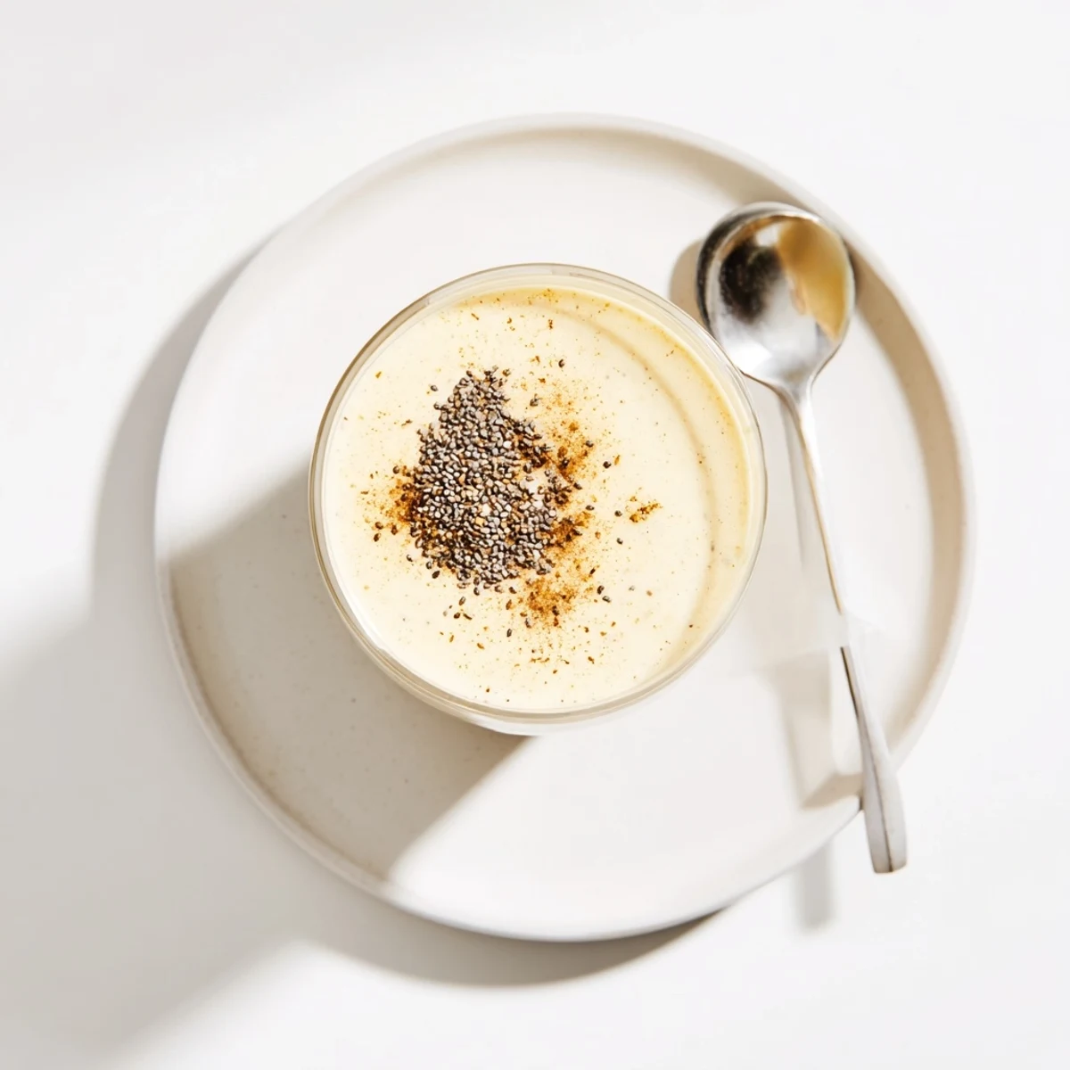 Creamy Greek yogurt banana smoothie poured into a tall glass topped with fresh banana slices