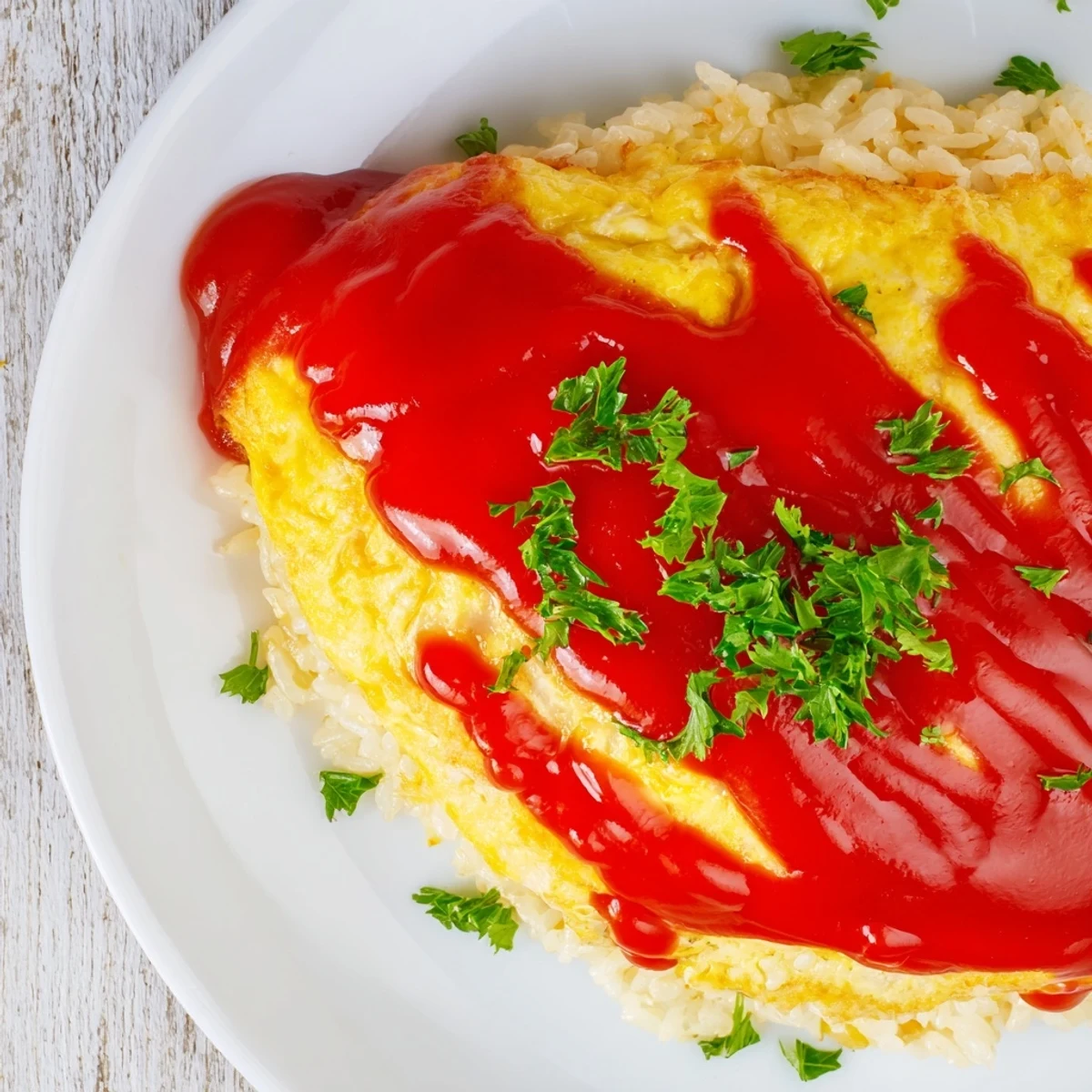 Japanese-style omurice served on a white plate with drizzled ketchup and chopped parsley garnish