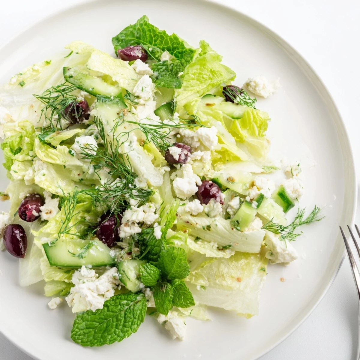Traditional Greek Maroulosalata featuring crisp lettuce, scallions, and herbs tossed in olive oil dressing topped with feta