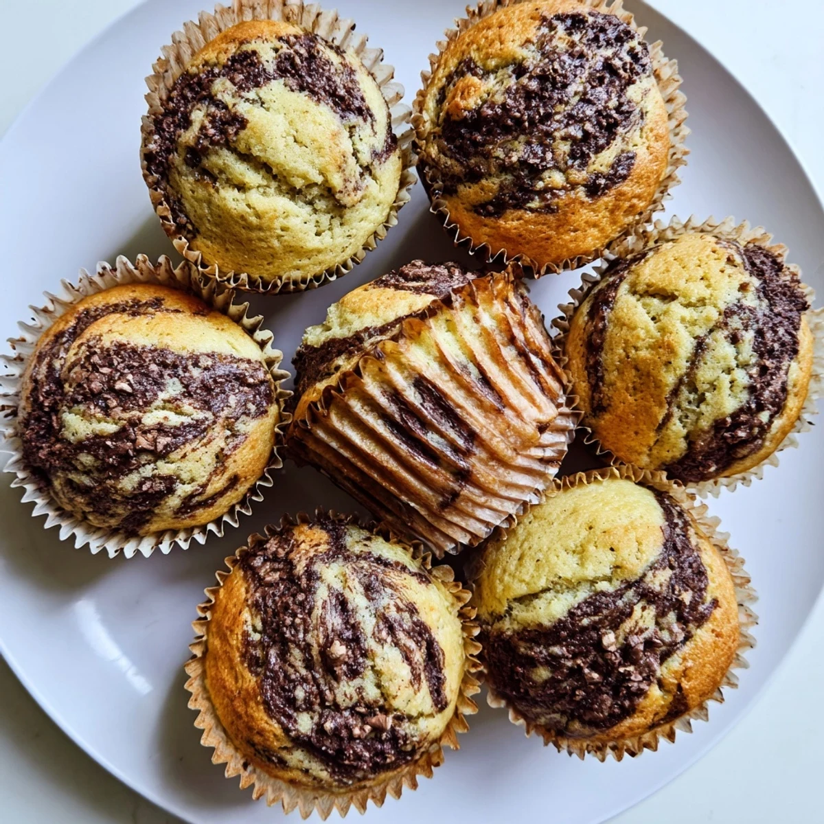 Moist banana breakfast muffins featuring melted Nutella marbled throughout the fluffy crumb