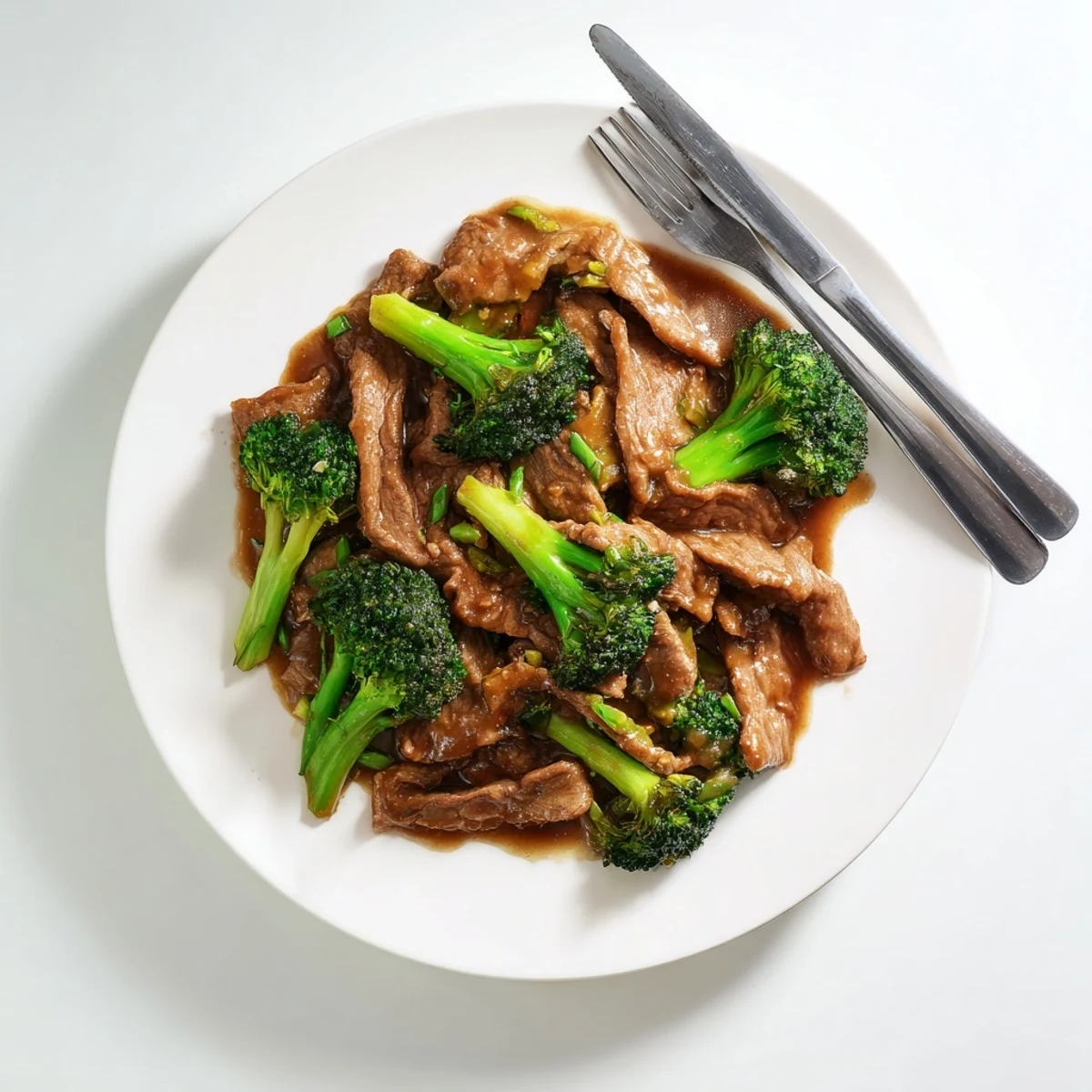 Savory Asian-style sauce with garlic and ginger simmers over beef strips and fresh green broccoli in hot wok