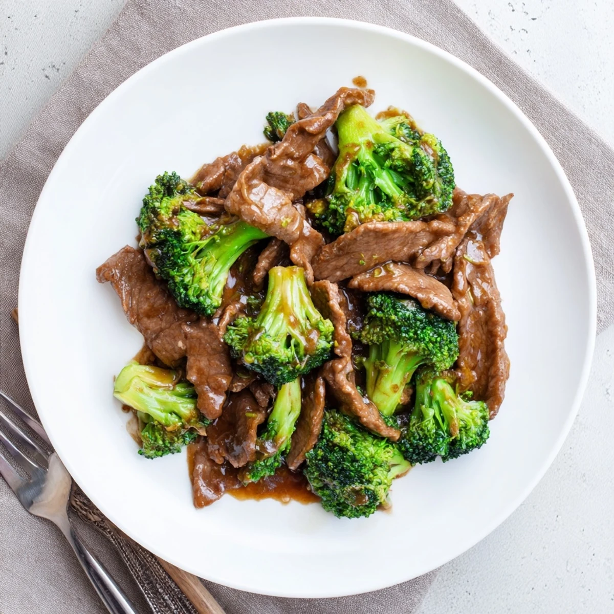 Homemade stir fry sauce with sesame oil and oyster sauce drizzled over sizzling beef and colorful broccoli pieces
