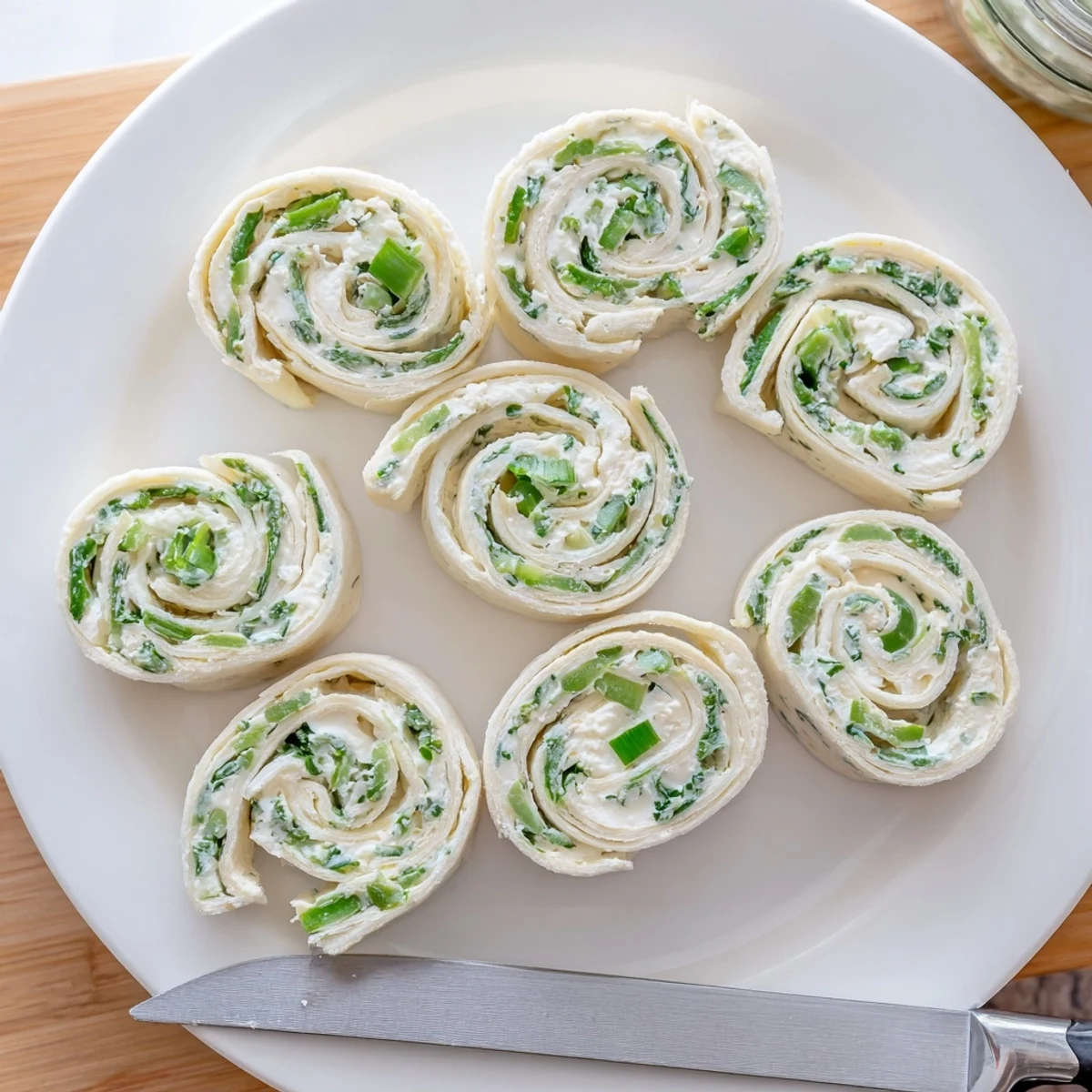 Close-up of sliced pickle dip pinwheels revealing the tangy dill pickle and herbed cream cheese spiral filling rolled inside soft flour tortillas