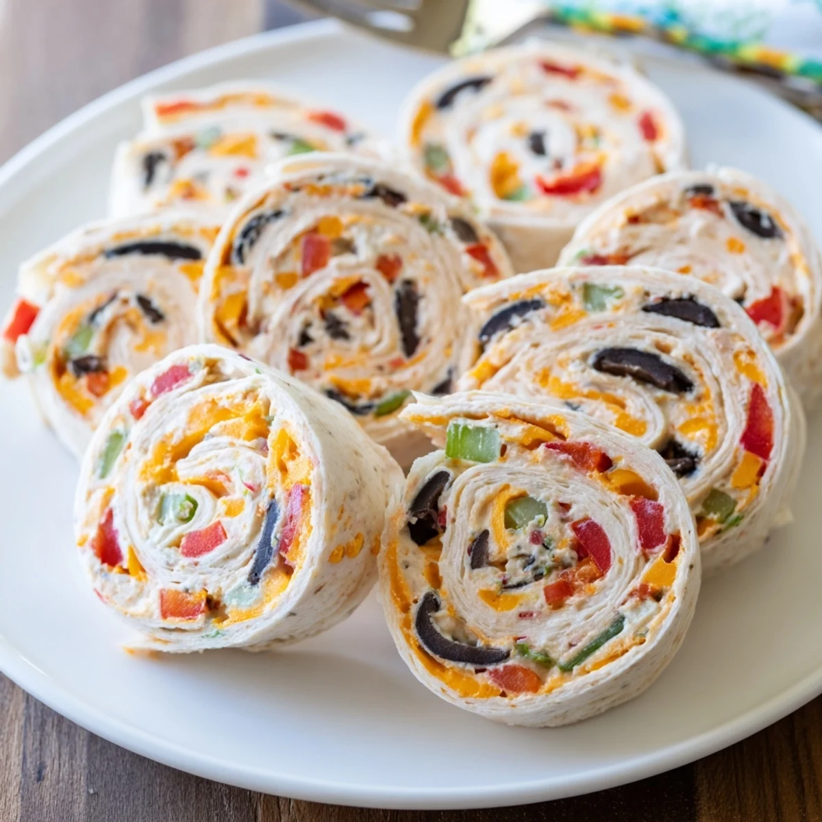 Close-up view of sliced easy tortilla pinwheels showcasing red peppers, green onions, and olives in cream cheese