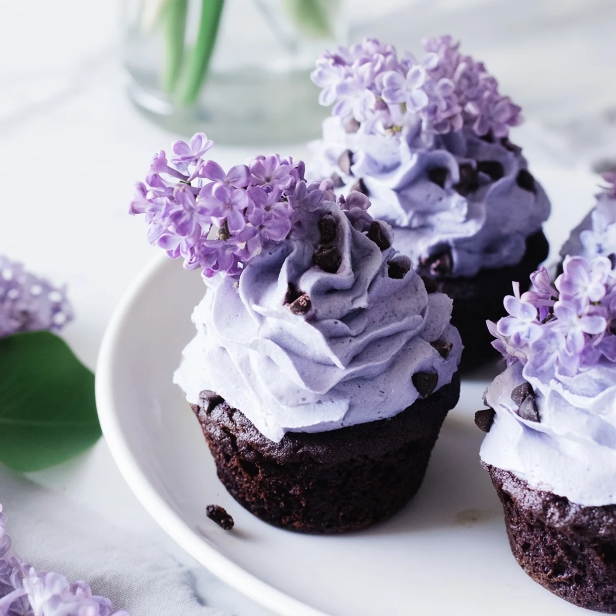 Rich lilac chocolate cupcakes decorated with edible flowers and served on a rustic wooden board for spring dessert