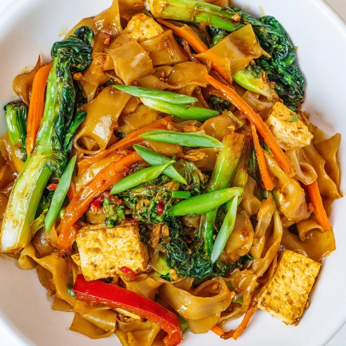 Steamy plate of vegan Pad See Ew featuring chewy rice noodles, Chinese broccoli, and protein-rich tofu