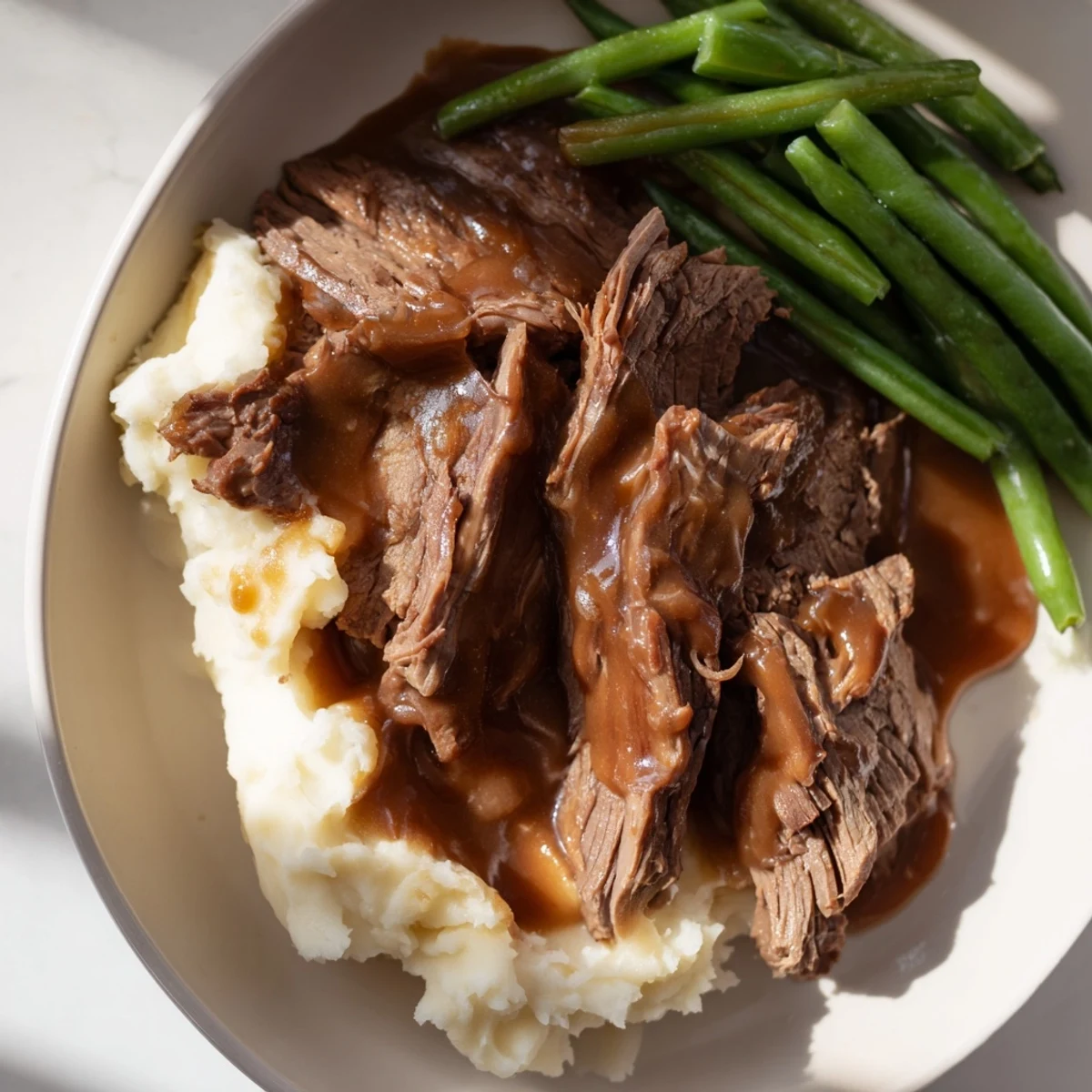 Hearty Southern style pot roast plate showcasing slow-braised beef in rich gravy served over creamy buttered potatoes