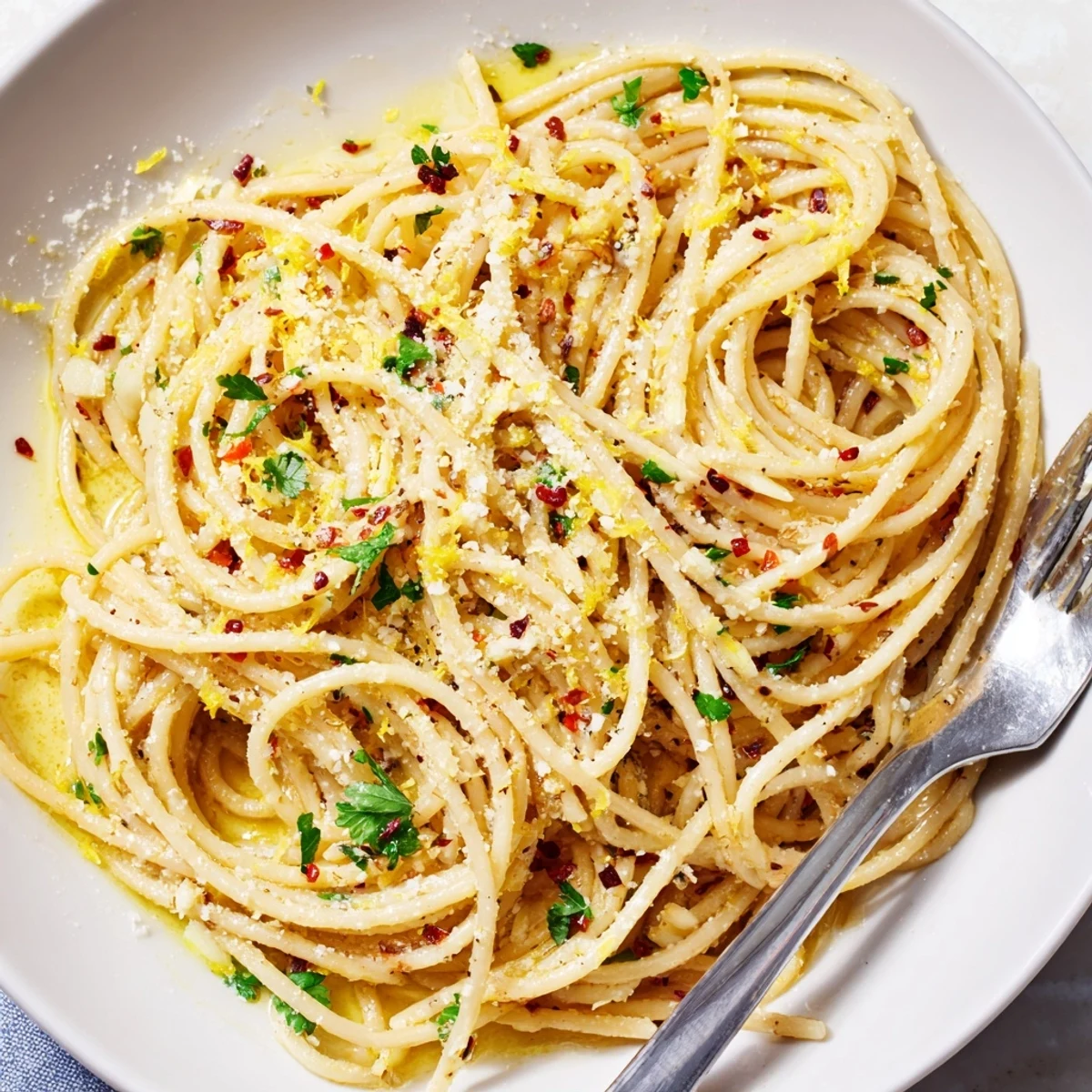 Close-up of garlic butter pasta strands glistening with olive oil and red pepper flakes