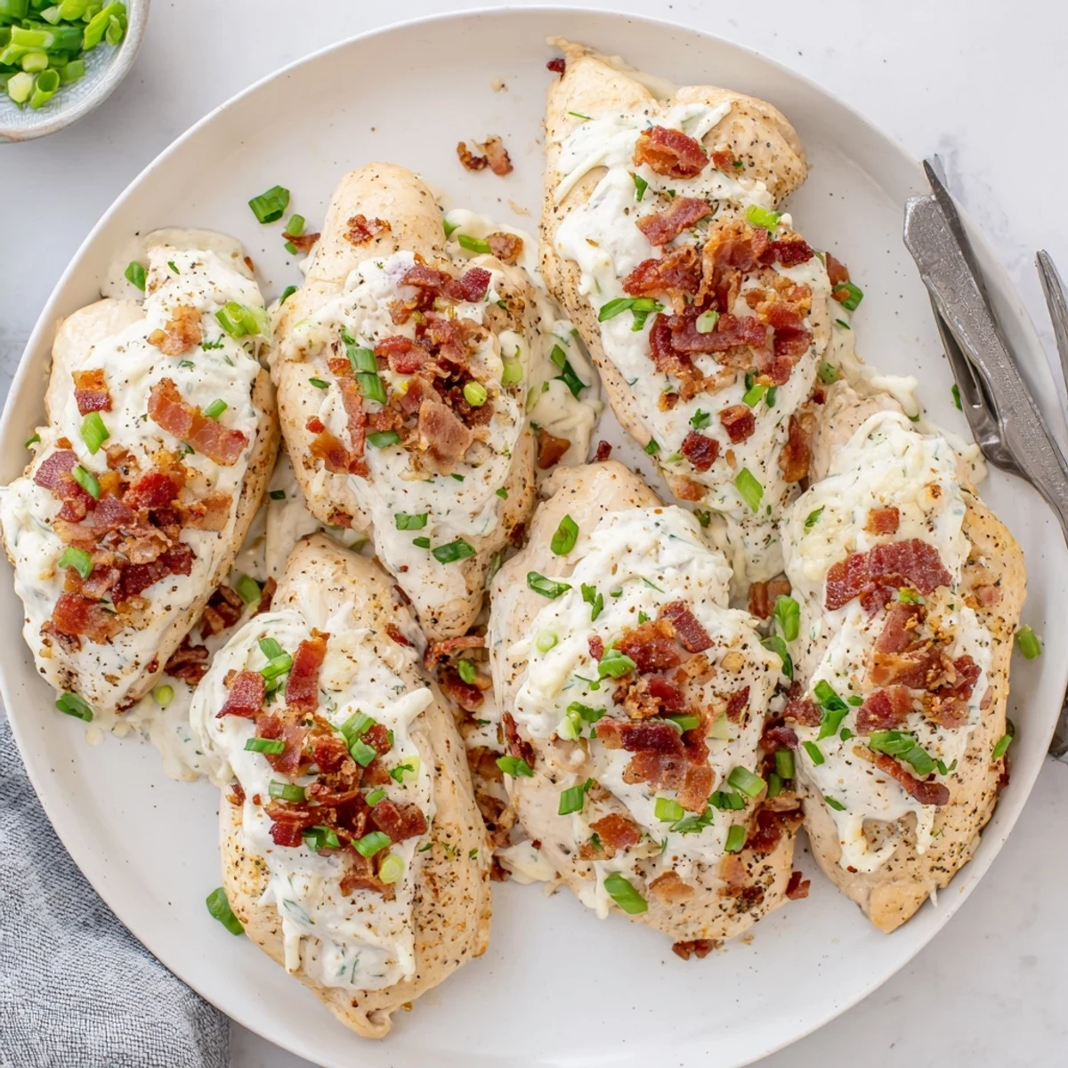 Creamy slow-cooked chicken breasts smothered in melted mozzarella and Parmesan cheese with bacon garnish