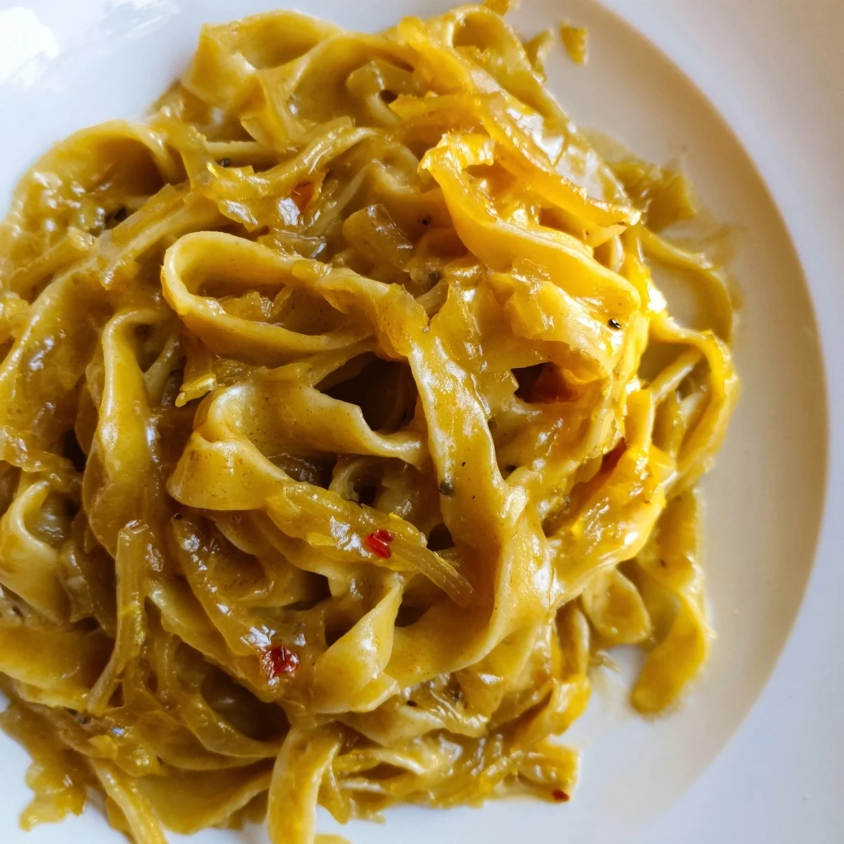 Creamy sweet heat caramelized onion fettuccine twirled on a fork with parmesan cheese sprinkled on top