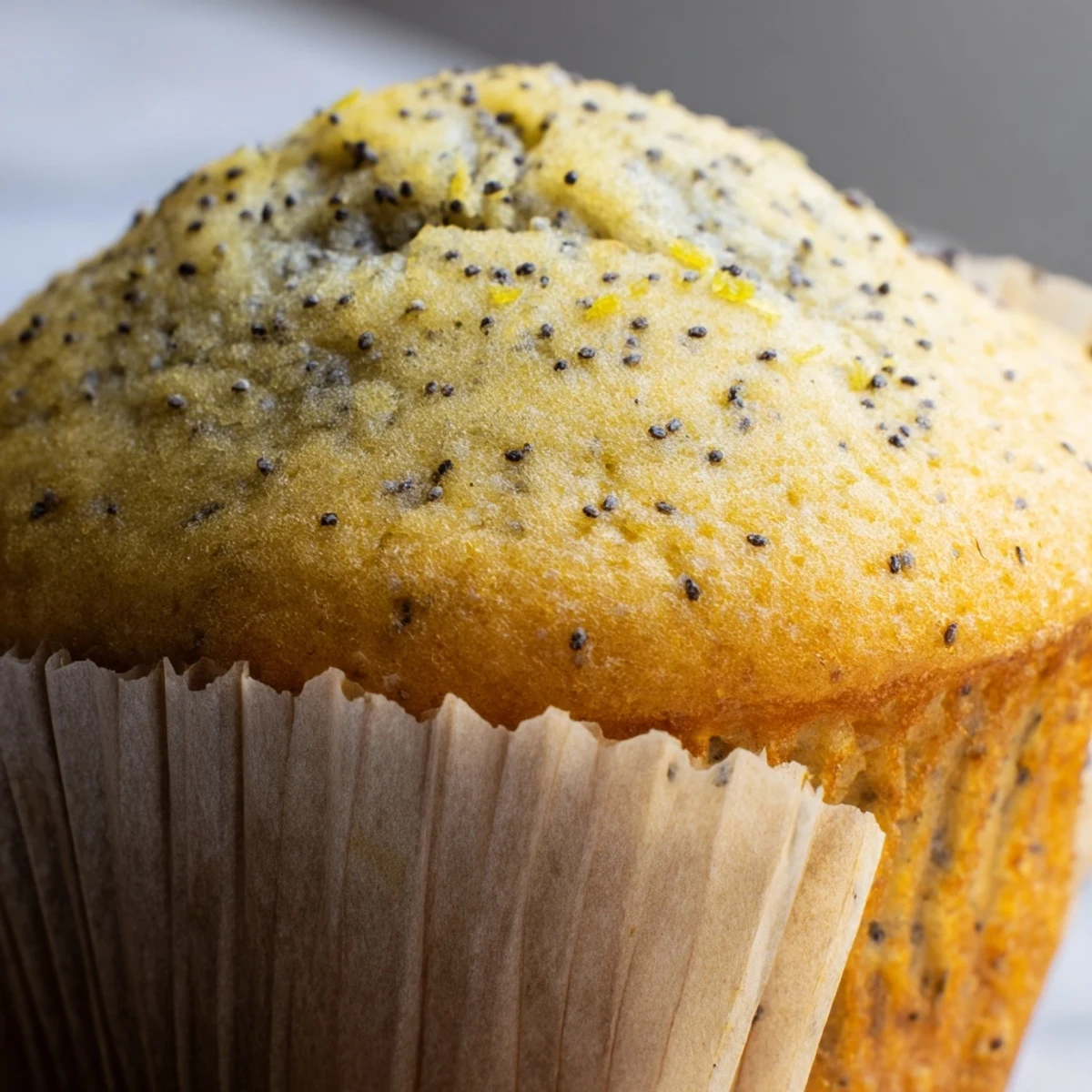 Golden lemon poppy seed muffins with domed tops fresh from the oven on a cooling rack