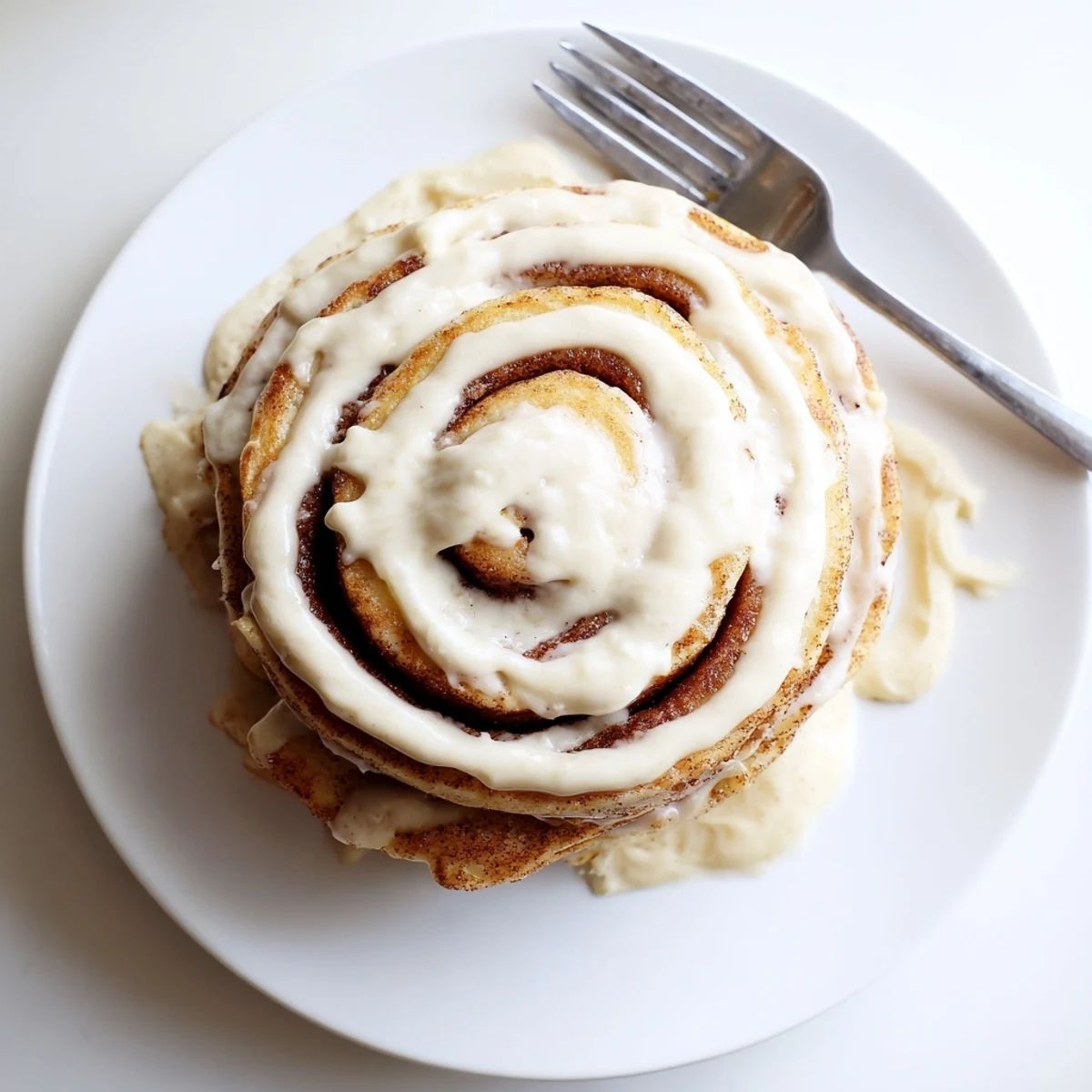 Fluffy pancakes spiraled with warm cinnamon sugar filling served on a white breakfast plate