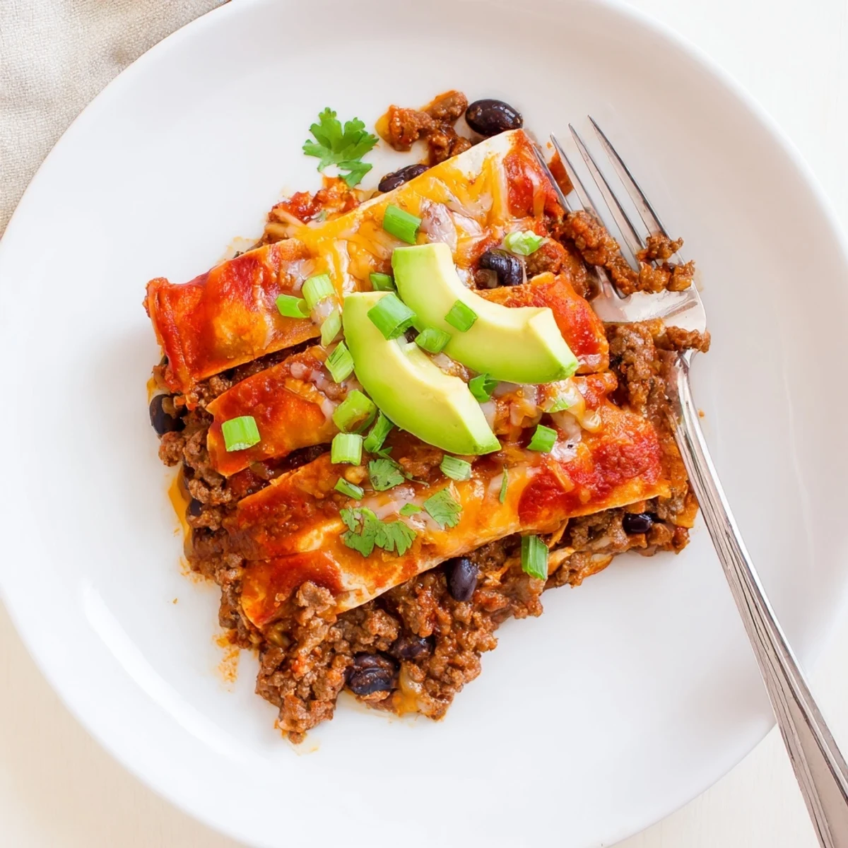 Beef Skillet Enchiladas bubbling in skillet with melted cheese, cilantro garnish