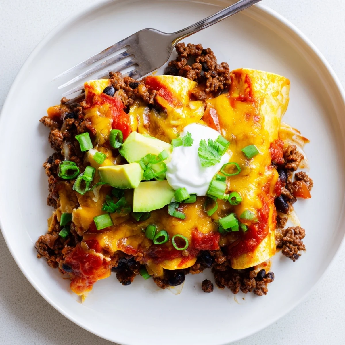 Hearty Beef Skillet Enchiladas served hot with avocado, sour cream dollop