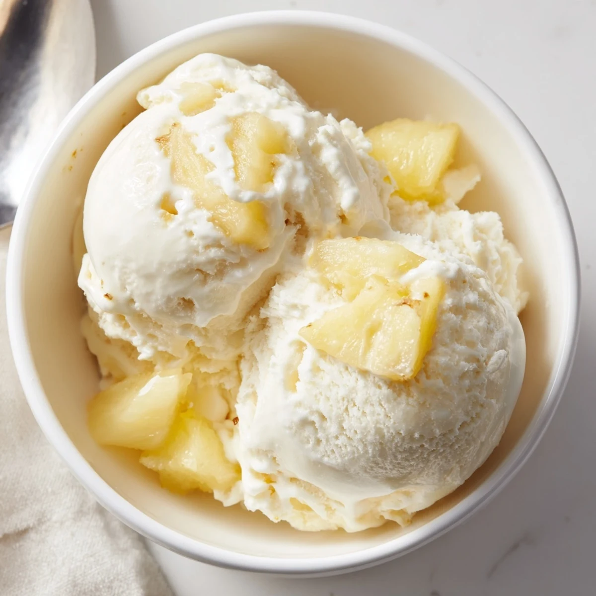 Creamy Pineapple Ice Cream served in a bowl with toasted coconut flakes